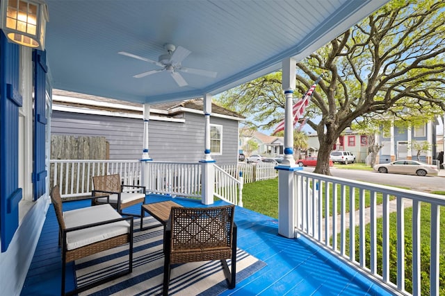 wooden terrace with outdoor lounge area, a lawn, a ceiling fan, a porch, and a residential view