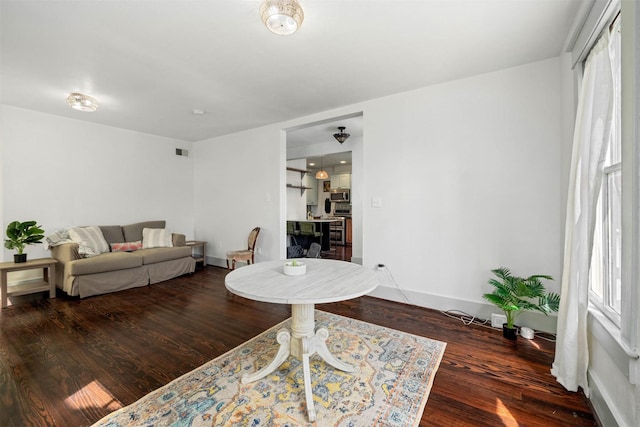 living area with visible vents, baseboards, and wood finished floors