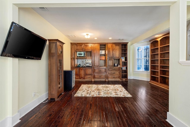 interior space featuring visible vents, baseboards, stainless steel microwave, dark wood finished floors, and backsplash