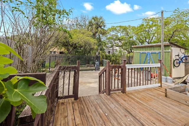 wooden terrace with an outdoor structure, a patio area, fence, and a storage shed