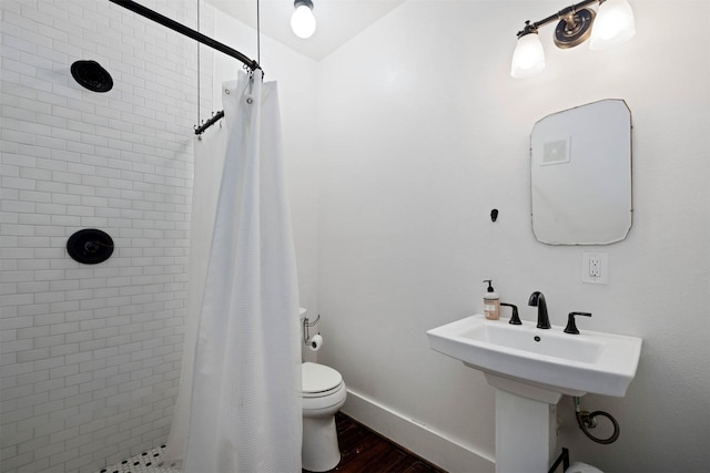 full bath with baseboards, a shower stall, toilet, and wood finished floors