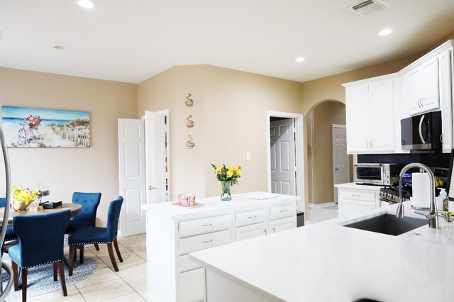 kitchen with arched walkways, visible vents, recessed lighting, stainless steel microwave, and a sink