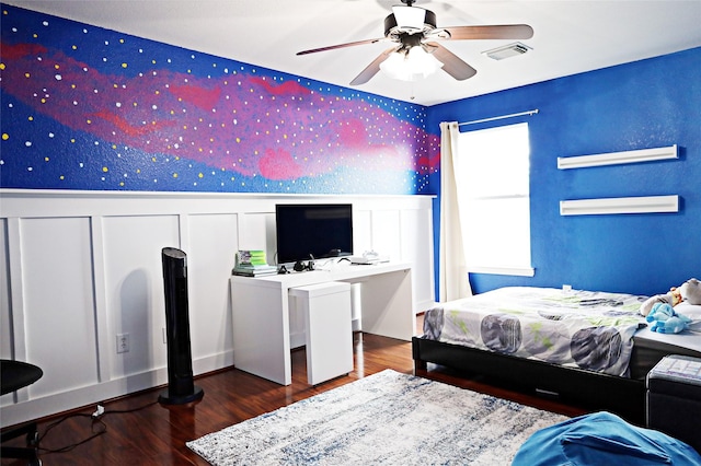bedroom featuring visible vents, a ceiling fan, wainscoting, wood finished floors, and wallpapered walls