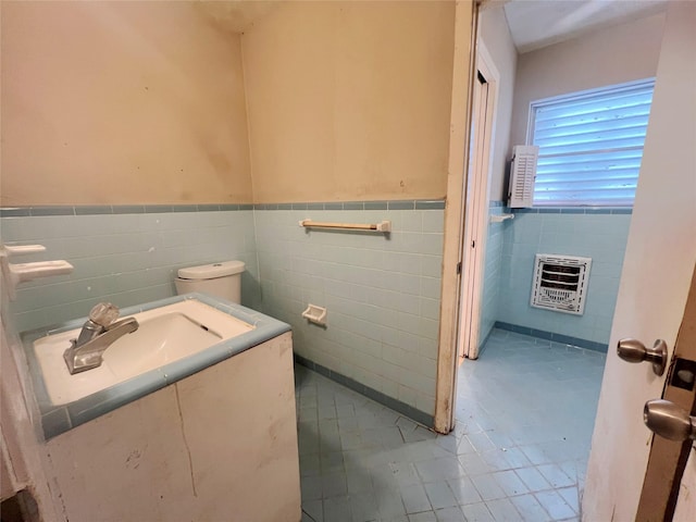 105 Longridge Dr, La Marque, TX 77568 - bathroom with a sink, tile walls, toilet, heating unit, and a wainscoted wall