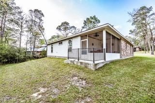 back of property with a sunroom and a lawn
