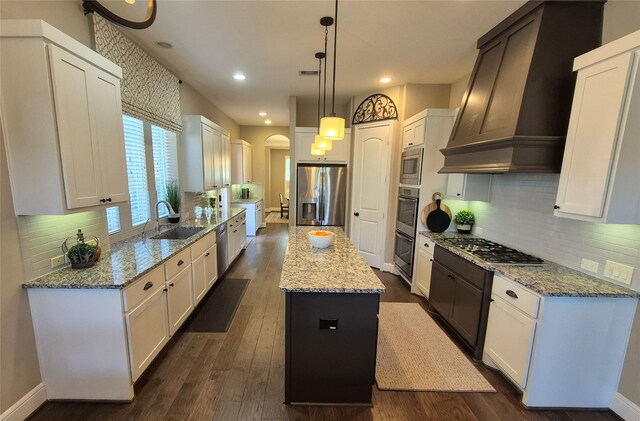 7106 Prairie Grass Ln, Katy, TX 77493 - kitchen with stainless steel appliances, a sink, a kitchen island, custom range hood, and white cabinets