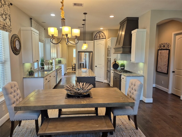 7106 Prairie Grass Ln, Katy, TX 77493 - dining space featuring dark wood-style floors, recessed lighting, arched walkways, baseboards, and a chandelier