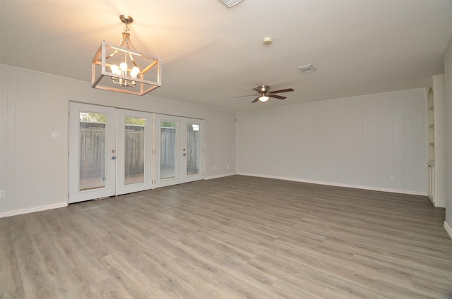 unfurnished room with light wood-style floors, ceiling fan with notable chandelier, visible vents, french doors, and baseboards