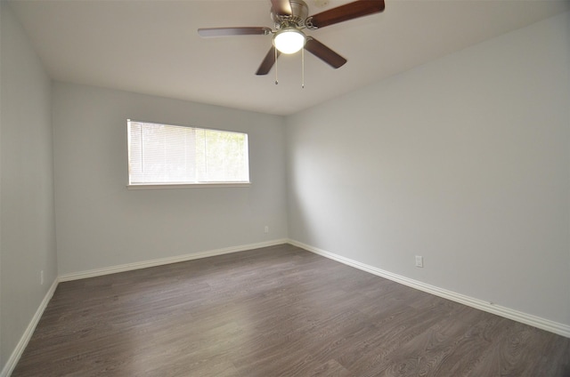 unfurnished room with baseboards, a ceiling fan, and dark wood finished floors