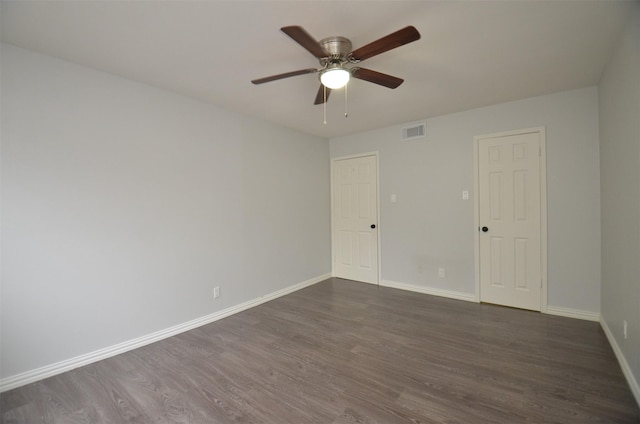 empty room with ceiling fan, baseboards, dark wood-style floors, and visible vents