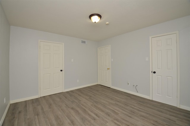 unfurnished room with visible vents, baseboards, and wood finished floors