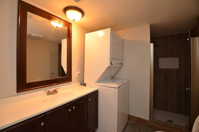 bathroom featuring a shower stall, stacked washer / dryer, and vanity