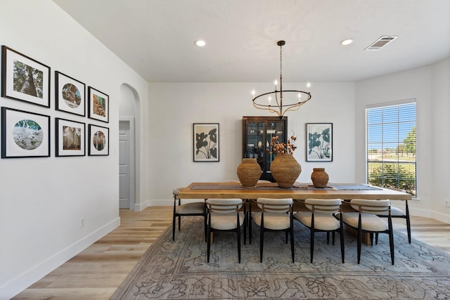 26719 Outback Dr, Katy, TX 77493 - dining area featuring baseboards, an inviting chandelier, light wood-style flooring, visible vents, and arched walkways