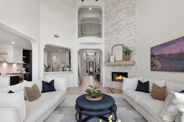 26719 Outback Dr, Katy, TX 77493 - living area featuring a stone fireplace, visible vents, light wood-style flooring, and a high ceiling