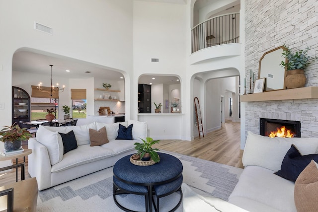 26719 Outback Dr, Katy, TX 77493 - living area with visible vents, a stone fireplace, arched walkways, and an inviting chandelier