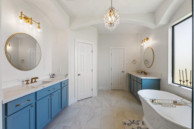 26719 Outback Dr, Katy, TX 77493 - bathroom featuring two vanities, an inviting chandelier, a freestanding tub, marble finish floor, and a sink