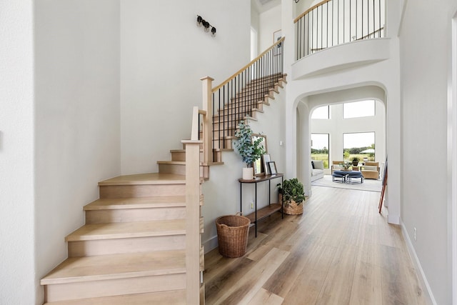 26719 Outback Dr, Katy, TX 77493 - stairway with arched walkways, wood finished floors, a towering ceiling, and baseboards