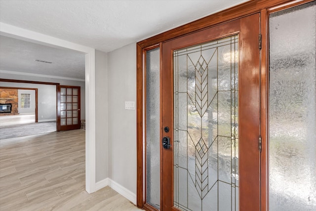foyer featuring visible vents, light wood-type flooring, crown molding, and baseboards