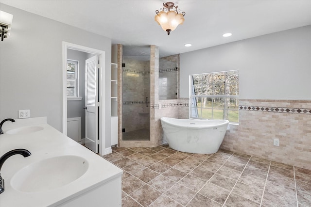bathroom featuring tile walls, a stall shower, and a sink