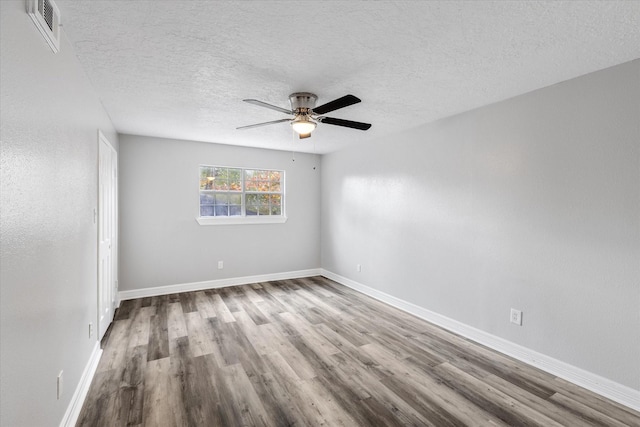 unfurnished room with a textured ceiling, visible vents, ceiling fan, and wood finished floors