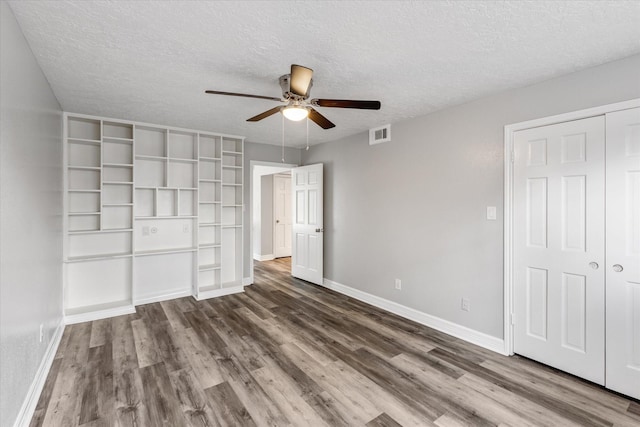 unfurnished bedroom featuring baseboards, visible vents, wood finished floors, and a textured ceiling