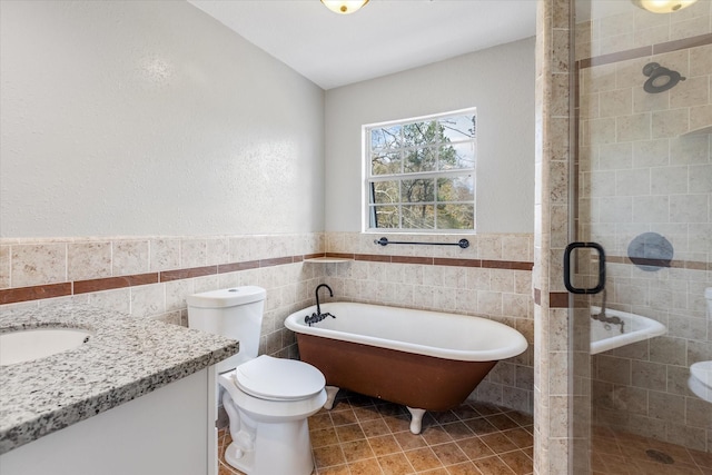 bathroom with tile walls, a freestanding bath, a shower stall, and vanity