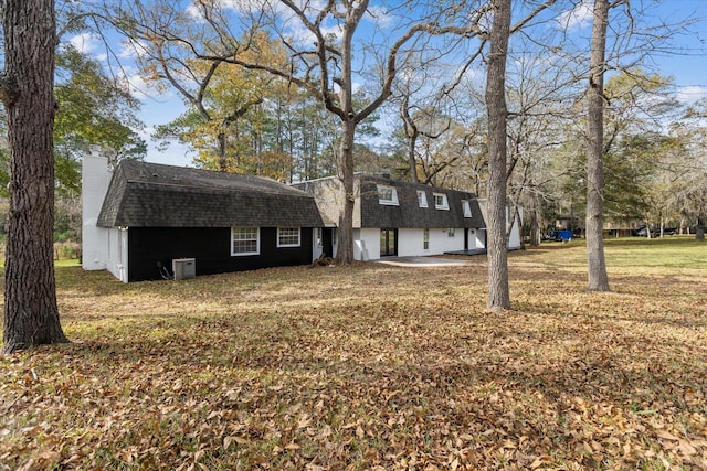exterior space featuring an outdoor structure, a lawn, a shingled roof, and a chimney