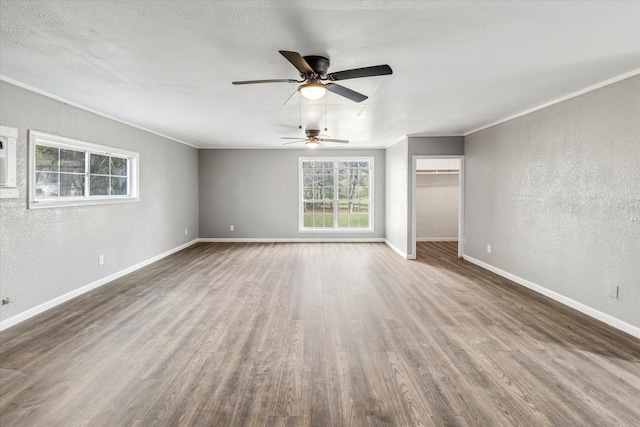 unfurnished bedroom with crown molding, a textured wall, wood finished floors, and baseboards