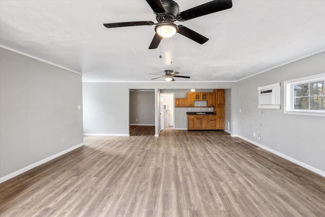 unfurnished living room with ceiling fan, light wood-type flooring, a wall mounted air conditioner, and baseboards