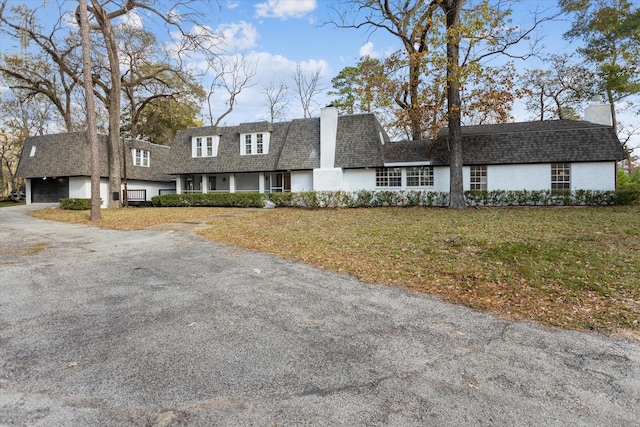 view of front of home featuring a chimney, a shingled roof, a front yard, and stucco siding