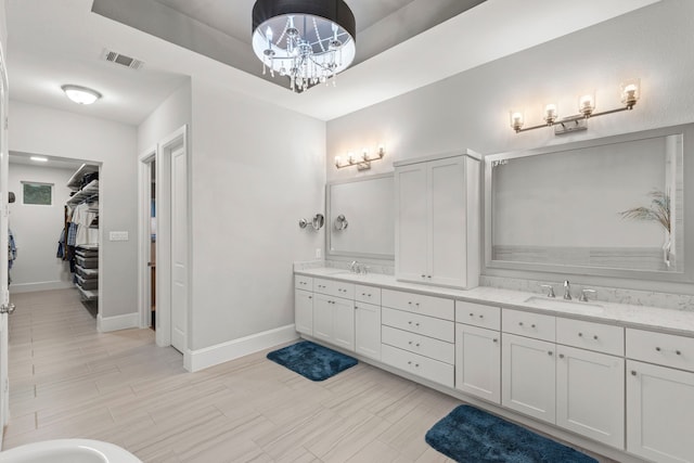 6931 Harvest Ln, Katy, TX 77493 - bathroom featuring baseboards, double vanity, visible vents, a tray ceiling, and a sink
