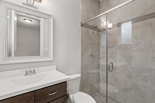 6931 Harvest Ln, Katy, TX 77493 - bathroom featuring toilet, a stall shower, a textured wall, and vanity