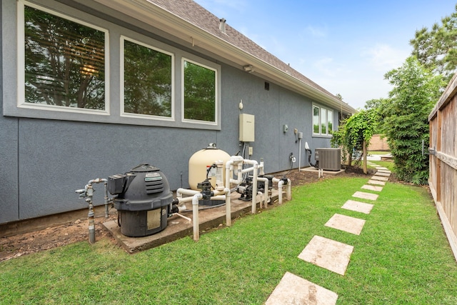6931 Harvest Ln, Katy, TX 77493 - rear view of property featuring central AC unit, fence, a lawn, and stucco siding