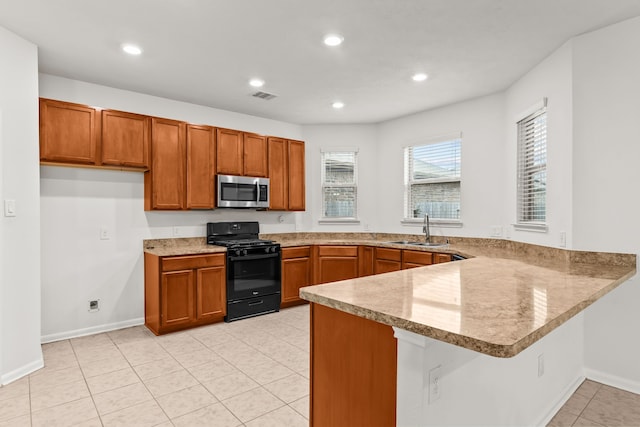 15922 Copper Springs Ln, Houston, TX 77084 - kitchen with a peninsula, black gas range oven, a sink, visible vents, and stainless steel microwave