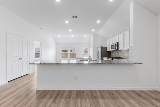 3319 Meadknoll Ln, Richmond, TX 77406 - kitchen with stainless steel appliances, vaulted ceiling, a sink, white cabinets, and light stone counters