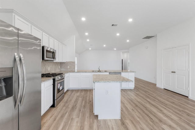 3319 Meadknoll Ln, Richmond, TX 77406 - kitchen featuring appliances with stainless steel finishes, a peninsula, a sink, light wood-style floors, and white cabinets