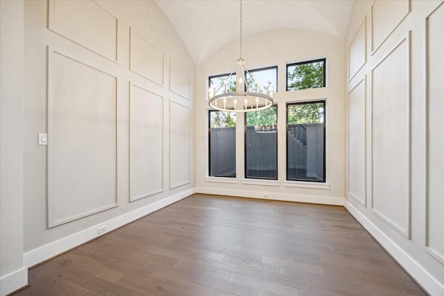 unfurnished dining area with a chandelier, dark wood-style floors, baseboards, and vaulted ceiling