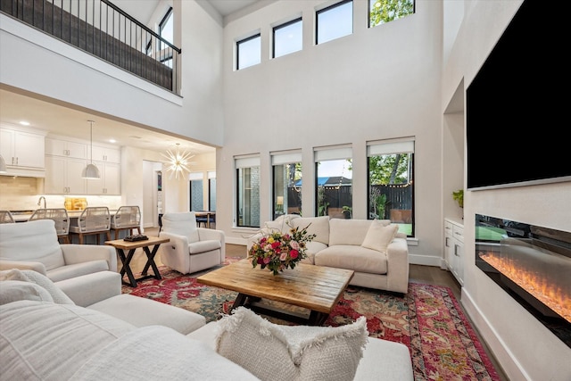 living room featuring wood finished floors, baseboards, a glass covered fireplace, and a wealth of natural light