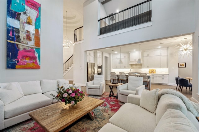 living area with stairway, baseboards, an inviting chandelier, and light wood finished floors