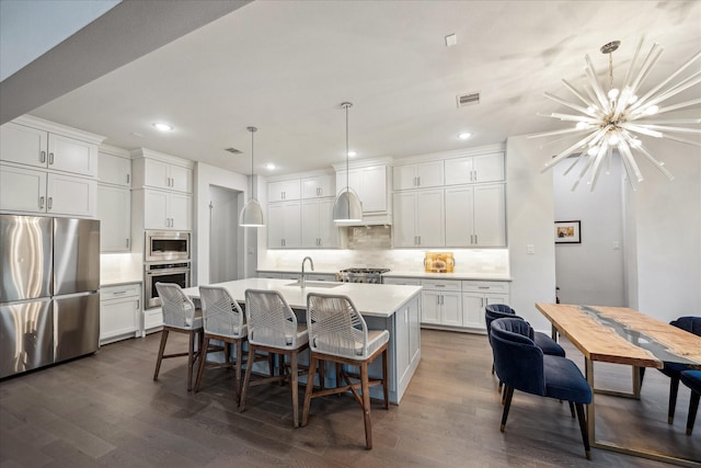 kitchen with tasteful backsplash, white cabinets, appliances with stainless steel finishes, and dark wood finished floors