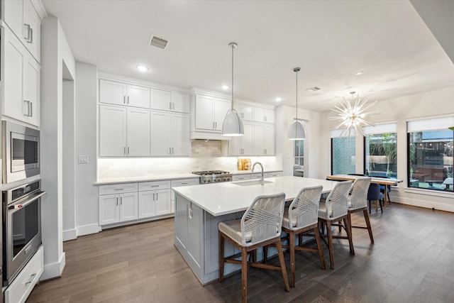 kitchen with tasteful backsplash, visible vents, a sink, a center island with sink, and stainless steel appliances