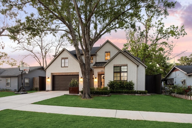 modern farmhouse with concrete driveway, brick siding, a standing seam roof, a yard, and fence