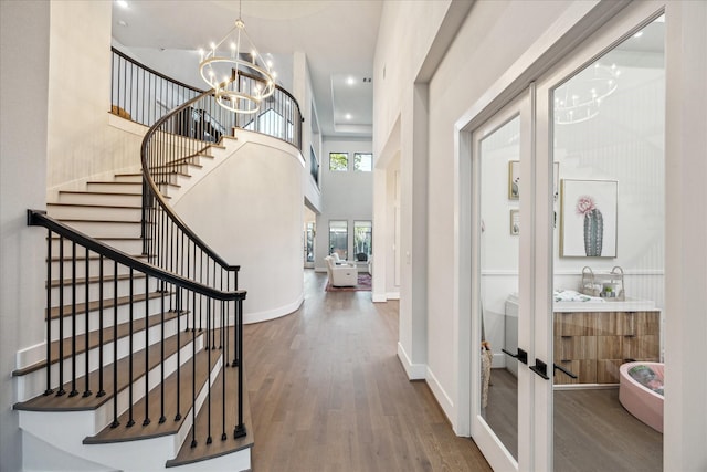 entrance foyer with stairway, baseboards, an inviting chandelier, and wood finished floors