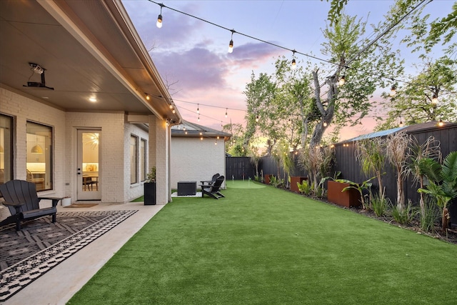 view of yard with central AC unit, a fenced backyard, and a patio