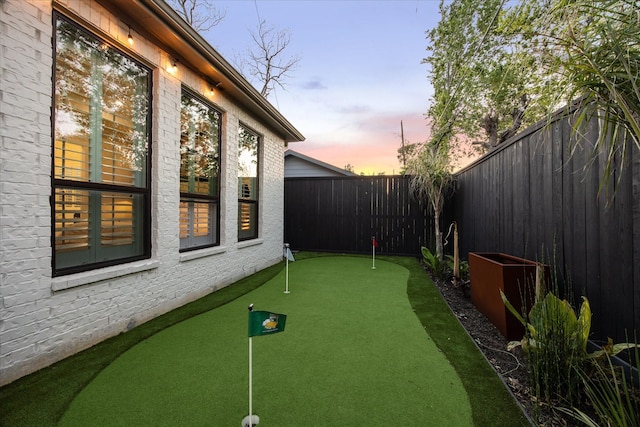 yard at dusk featuring a fenced backyard