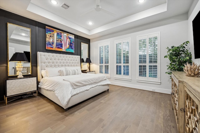 bedroom featuring visible vents, baseboards, a raised ceiling, and wood finished floors