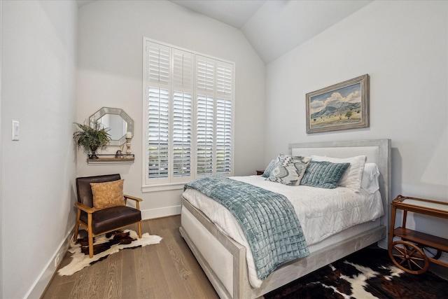 bedroom with baseboards, vaulted ceiling, and wood finished floors
