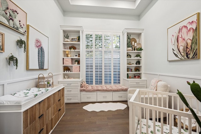 bedroom featuring dark wood-style flooring and a nursery area