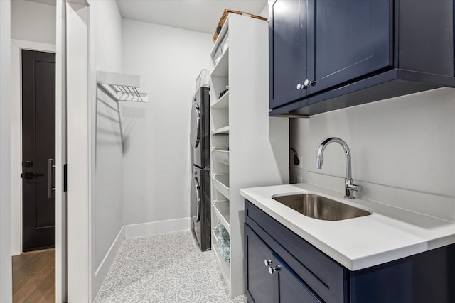 laundry room featuring baseboards, stacked washing maching and dryer, a sink, and cabinet space