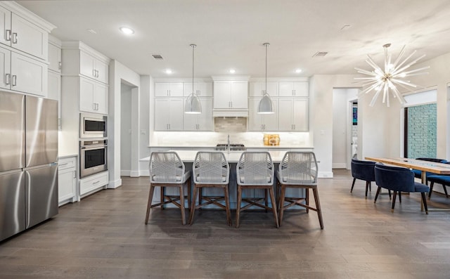 kitchen featuring tasteful backsplash, visible vents, appliances with stainless steel finishes, a kitchen island with sink, and light countertops